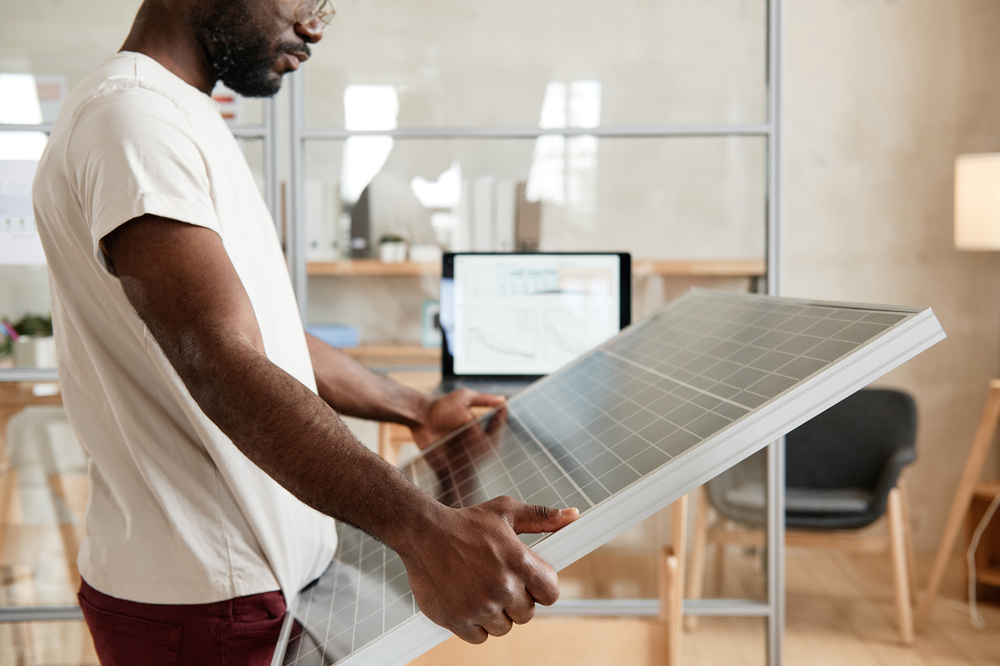 Serious African engineer holding solar battery in his hands during work at office